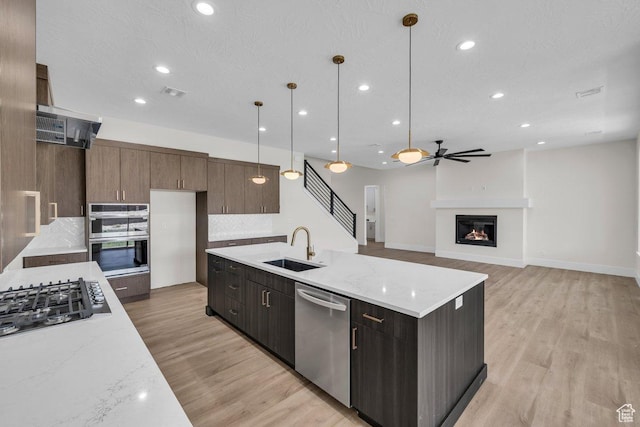 21 W Elinor Ln, Washington, UT 84780 - kitchen featuring stainless steel appliances, backsplash, light wood-type flooring, a glass covered fireplace, and recessed lighting