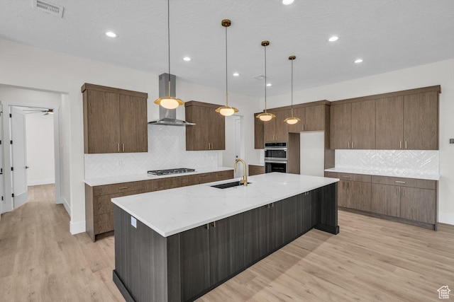 21 W Elinor Ln, Washington, UT 84780 - kitchen with wall chimney range hood, gas stovetop, backsplash, light wood-style floors, and stainless steel double oven