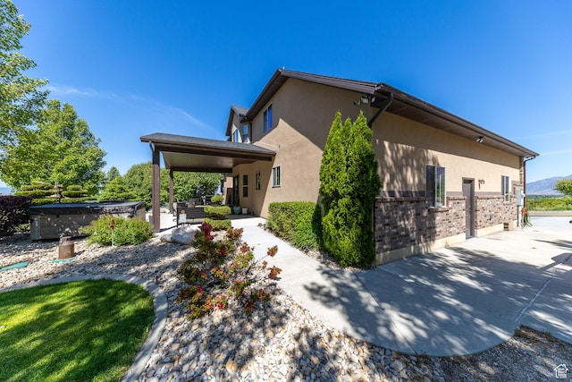 39 E 1800 S, Perry, UT 84302 - view of side of home with a hot tub, a patio area, stucco siding, and brick siding