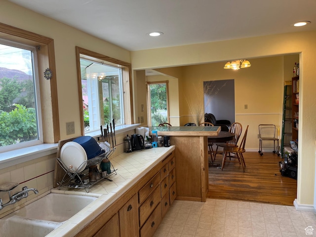 102 N 300 E, Moab, UT 84532 - kitchen with tile countertops, brown cabinets, a chandelier, recessed lighting, and backsplash