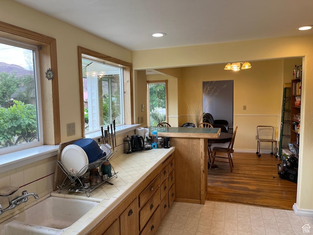 102 N 300 E, Moab, UT 84532 - kitchen featuring tile countertops, healthy amount of natural light, brown cabinetry, recessed lighting, and a chandelier