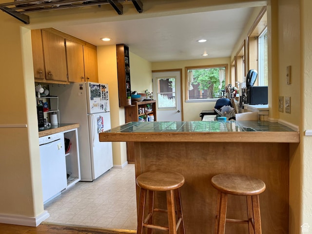 102 N 300 E, Moab, UT 84532 - kitchen featuring tile countertops, a breakfast bar area, a peninsula, and recessed lighting