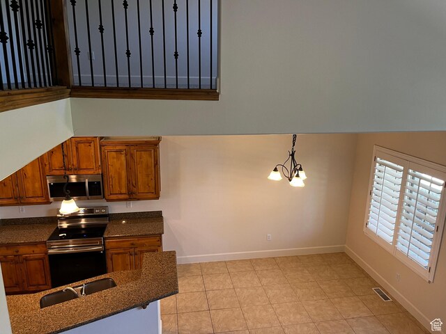 933 N 900 W, Orem, UT 84057 - kitchen featuring appliances with stainless steel finishes, brown cabinets, a chandelier, dark stone counters, and light tile patterned floors