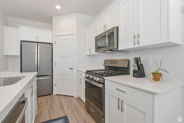 1304 E Weyburn Ln S Unit 10, Holladay, UT 84117 - kitchen with appliances with stainless steel finishes, white cabinets, light wood finished floors, recessed lighting, and light stone countertops