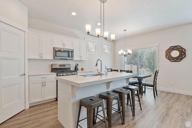 1304 E Weyburn Ln S Unit 10, Holladay, UT 84117 - kitchen with appliances with stainless steel finishes, a chandelier, light wood-style floors, an island with sink, and white cabinetry