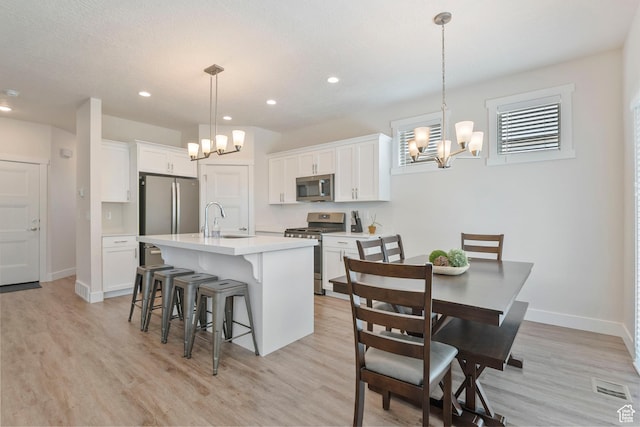 1304 E Weyburn Ln S Unit 10, Holladay, UT 84117 - kitchen featuring stainless steel appliances, a chandelier, a kitchen breakfast bar, light countertops, and white cabinetry