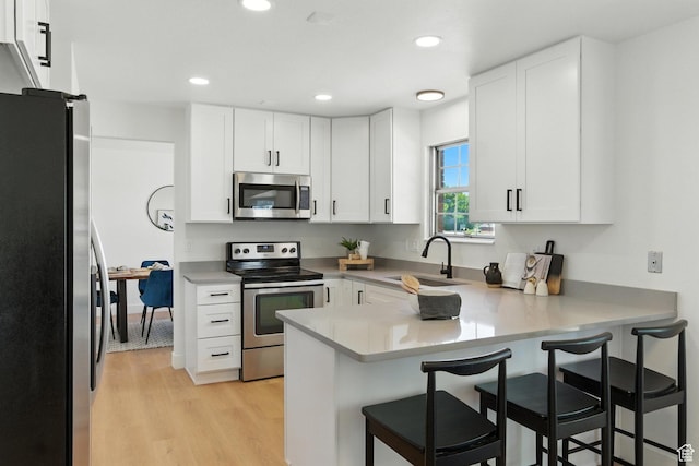 585 N 700 E, Nephi, UT 84648 - kitchen featuring appliances with stainless steel finishes, a peninsula, white cabinets, light wood finished floors, and recessed lighting