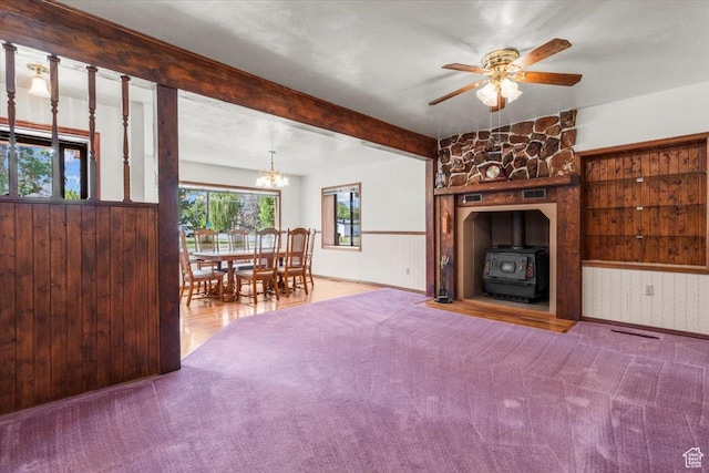 294 W 200 N, Mount Pleasant, UT 84647 - carpeted living area with a wood stove, a chandelier, a ceiling fan, wood walls, and a wainscoted wall