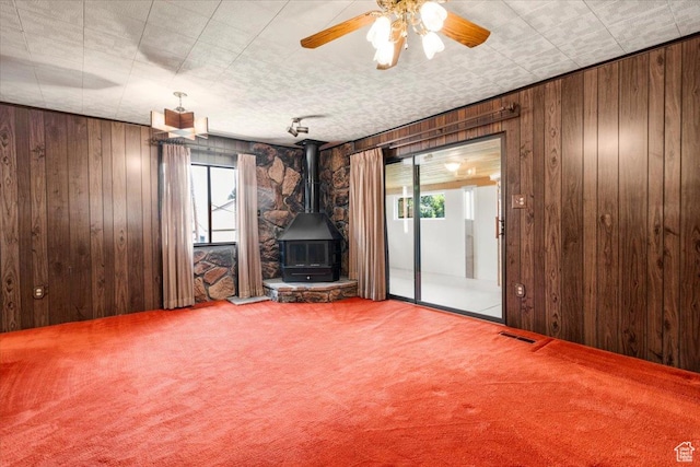 294 W 200 N, Mount Pleasant, UT 84647 - unfurnished living room featuring carpet, a wood stove, healthy amount of natural light, wood walls, and a ceiling fan