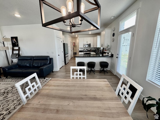1038 W 980 S Unit 312, American Fork, UT 84003 - dining area with a chandelier, healthy amount of natural light, light wood-type flooring, and a textured ceiling