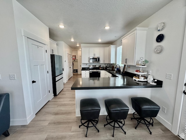 1038 W 980 S Unit 312, American Fork, UT 84003 - kitchen featuring appliances with stainless steel finishes, a peninsula, dark countertops, a kitchen bar, and white cabinetry