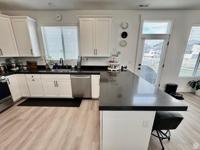 1038 W 980 S Unit 312, American Fork, UT 84003 - kitchen with appliances with stainless steel finishes, a peninsula, white cabinetry, and light wood finished floors