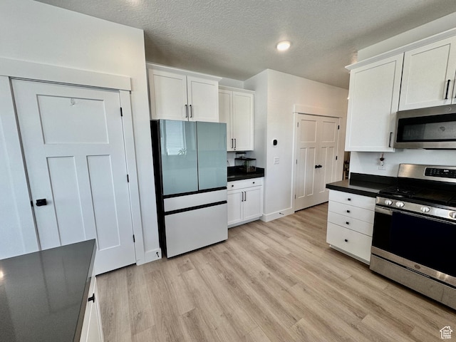 1038 W 980 S Unit 312, American Fork, UT 84003 - kitchen featuring appliances with stainless steel finishes, dark countertops, light wood-type flooring, white cabinetry, and a textured ceiling