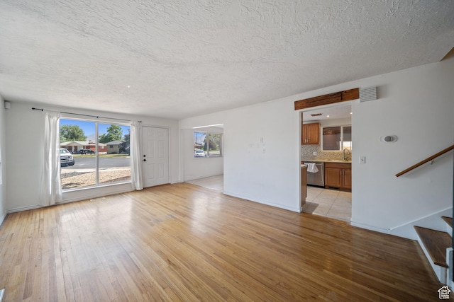 5154 S Lori Way, Salt Lake City, UT 84117 - unfurnished living room featuring light wood-style flooring, stairs, and a textured ceiling