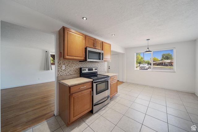 5154 S Lori Way, Salt Lake City, UT 84117 - kitchen featuring appliances with stainless steel finishes, light countertops, a textured ceiling, backsplash, and brown cabinets