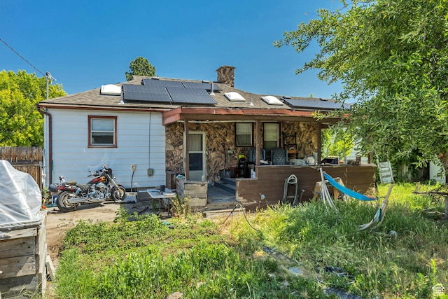 322 E Crawford Ave, Murray, UT 84107 - rear view of house featuring solar panels, a chimney, stone siding, and a shingled roof