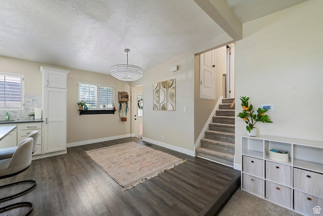 6764 S Enchanted Dr E, Midvale, UT 84047 - foyer entrance featuring a chandelier, dark wood finished floors, a textured ceiling, and stairs