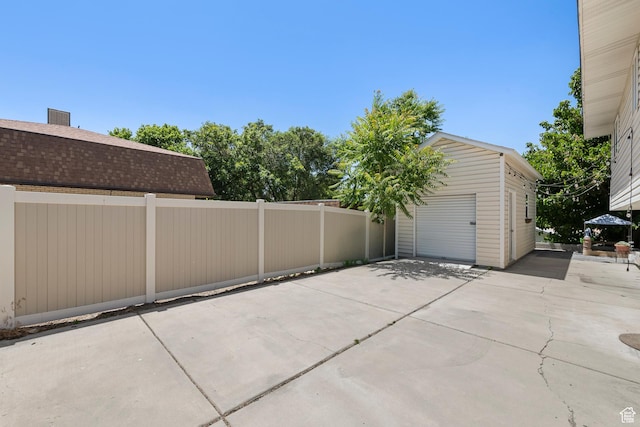 6764 S Enchanted Dr E, Midvale, UT 84047 - view of patio / terrace featuring a garage, driveway, and a storage shed