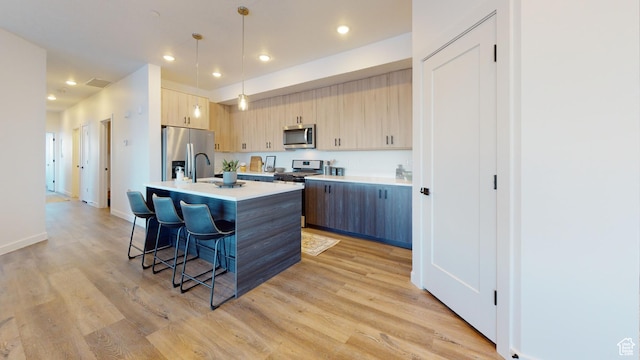 1378 S Sawmill Blvd Unit 7-703, Heber City, UT 84032 - kitchen featuring stainless steel appliances, light countertops, a kitchen bar, light wood-style floors, and an island with sink