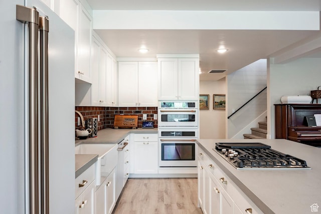 905 S Coldwater Way, Midway, UT 84049 - kitchen with high end refrigerator, stainless steel gas stovetop, white double oven, decorative backsplash, and white cabinets