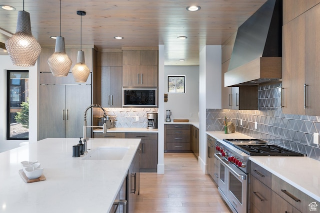 13202 N Alexis Dr, Heber City, UT 84036 - kitchen featuring range with two ovens, wall chimney range hood, modern cabinets, light wood-style flooring, and black microwave