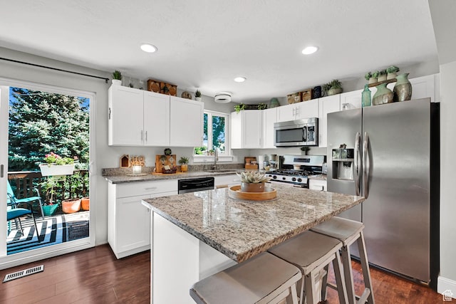 604 W 1750 N, Clinton, UT 84015 - kitchen with stainless steel appliances, white cabinets, dark wood finished floors, light stone counters, and a kitchen breakfast bar