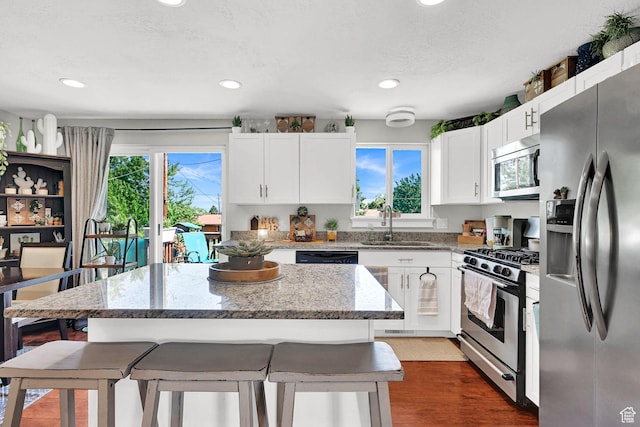 604 W 1750 N, Clinton, UT 84015 - kitchen with appliances with stainless steel finishes, a kitchen bar, light stone countertops, a kitchen island, and recessed lighting