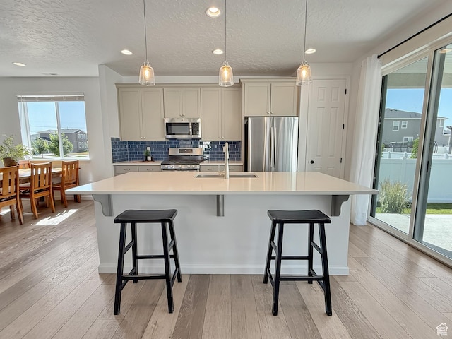998 W 850 S, Springville, UT 84663 - kitchen with stainless steel appliances, a textured ceiling, light countertops, a center island with sink, and light wood-style floors