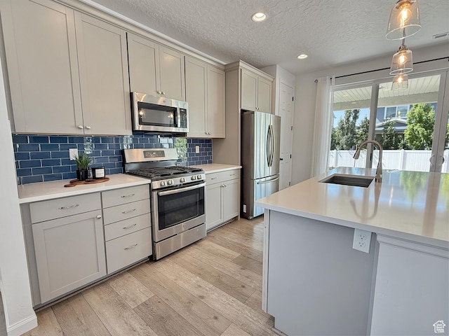 998 W 850 S, Springville, UT 84663 - kitchen with appliances with stainless steel finishes, light wood-style flooring, light countertops, backsplash, and pendant lighting