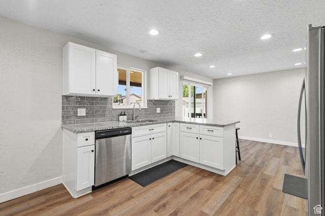 2234 W 300 N, West Point, UT 84015 - kitchen featuring appliances with stainless steel finishes, a peninsula, white cabinetry, light wood-style flooring, and recessed lighting