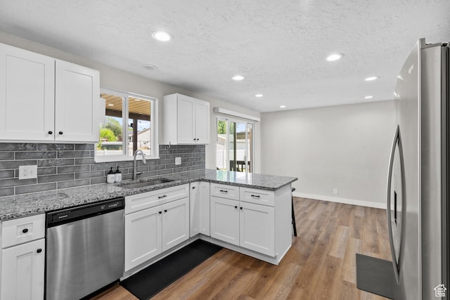 2234 W 300 N, West Point, UT 84015 - kitchen with stainless steel appliances, a peninsula, white cabinets, light stone countertops, and plenty of natural light