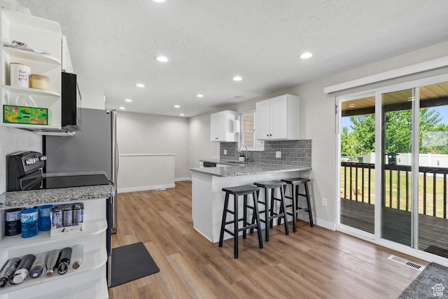 2234 W 300 N, West Point, UT 84015 - kitchen featuring a breakfast bar, white cabinets, light wood-type flooring, open shelves, and decorative backsplash
