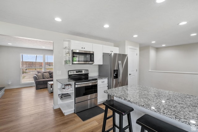 2234 W 300 N, West Point, UT 84015 - kitchen with appliances with stainless steel finishes, light wood finished floors, white cabinetry, a breakfast bar area, and recessed lighting