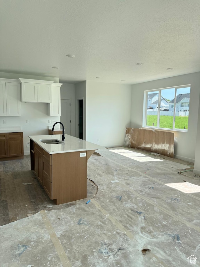 118 N 825 W, Clearfield, UT 84015 - kitchen featuring a center island with sink, open floor plan, a textured ceiling, white cabinets, and light countertops