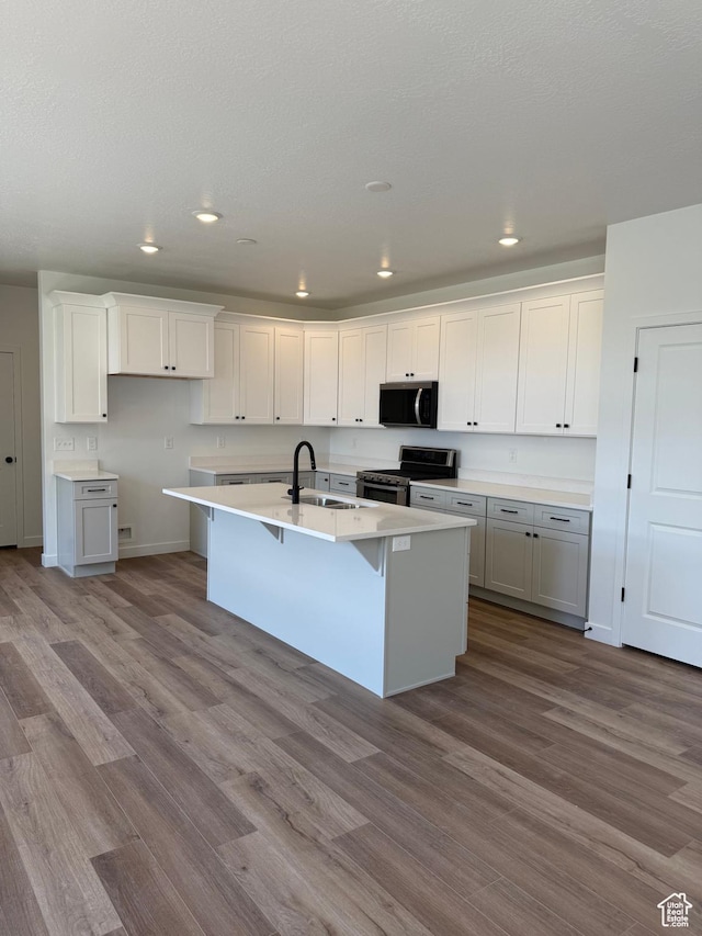 274 N 825 W, Clearfield, UT 84015 - kitchen with stainless steel range with electric cooktop, wood finished floors, an island with sink, recessed lighting, and a breakfast bar area