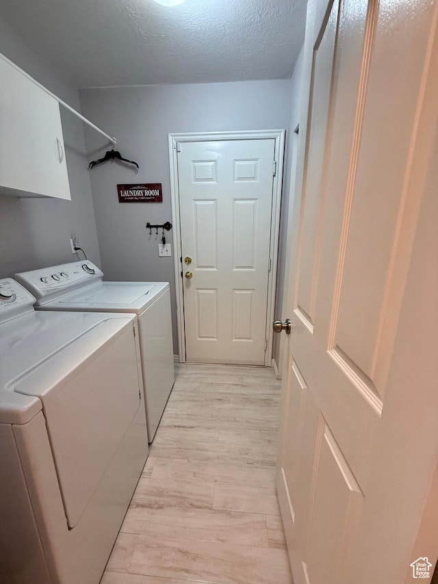 7089 S Brittany Town Dr, West Jordan, UT 84084 - laundry area featuring washer and clothes dryer, light wood-style flooring, cabinet space, and a textured ceiling