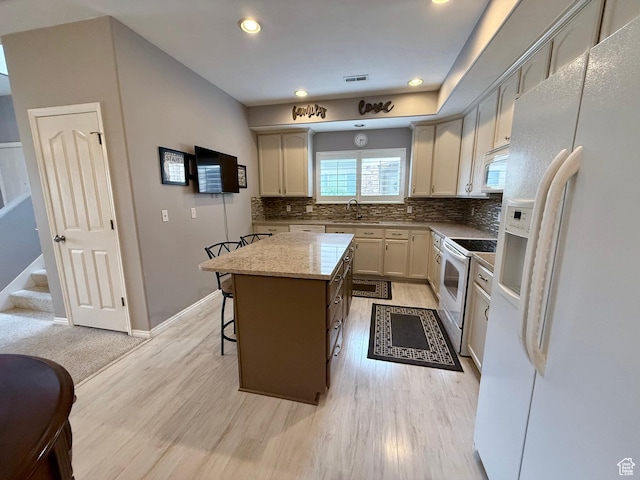 7089 S Brittany Town Dr, West Jordan, UT 84084 - kitchen featuring white appliances, a center island, tasteful backsplash, a breakfast bar area, and light wood-type flooring