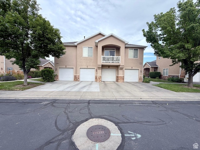 7089 S Brittany Town Dr, West Jordan, UT 84084 - view of front facade featuring stucco siding, stone siding, a garage, concrete driveway, and a balcony