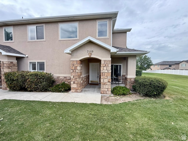 7089 S Brittany Town Dr, West Jordan, UT 84084 - view of front of home with stone siding, stucco siding, and a front lawn
