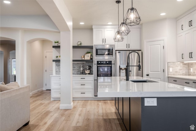 2979 E 3610th Cir S, St George, UT 84790 - kitchen featuring appliances with stainless steel finishes, open shelves, arched walkways, decorative backsplash, and white cabinetry