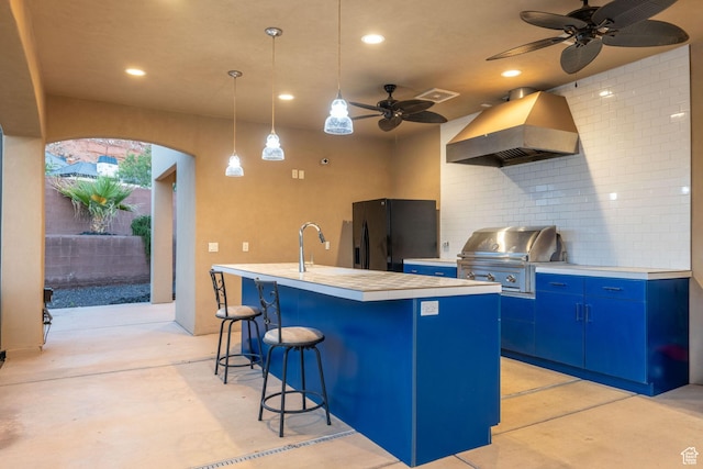 2979 E 3610th Cir S, St George, UT 84790 - kitchen featuring ventilation hood, black fridge with ice dispenser, blue cabinets, concrete flooring, and a ceiling fan
