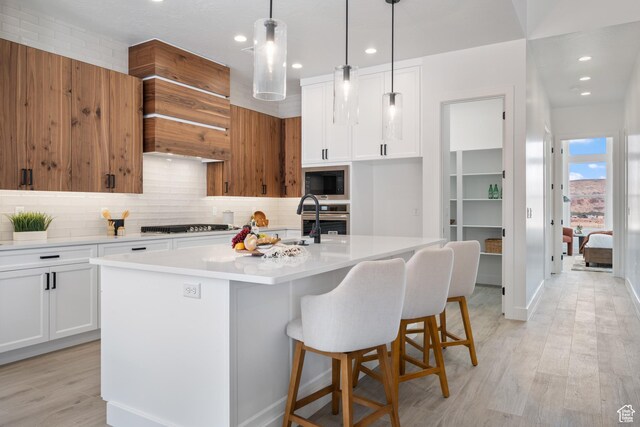 794 S 1690 W, Hurricane, UT 84737 - kitchen featuring black microwave, decorative backsplash, stainless steel oven, light countertops, and a center island with sink