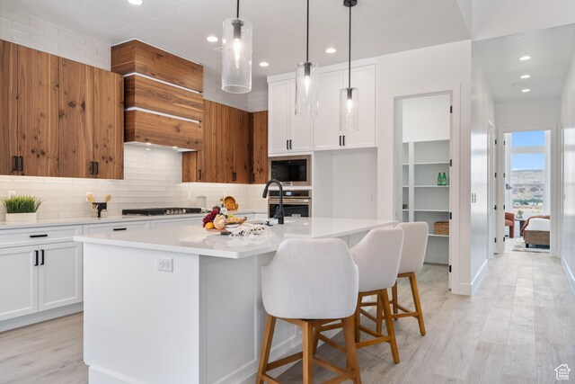 794 S 1690 W, Hurricane, UT 84737 - kitchen with black microwave, decorative backsplash, light countertops, oven, and a center island with sink