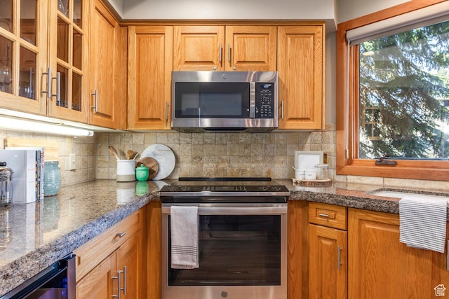 7560 Ridge Dr Unit 10, Park City, UT 84060 - kitchen featuring stainless steel appliances, brown cabinets, glass insert cabinets, and decorative backsplash
