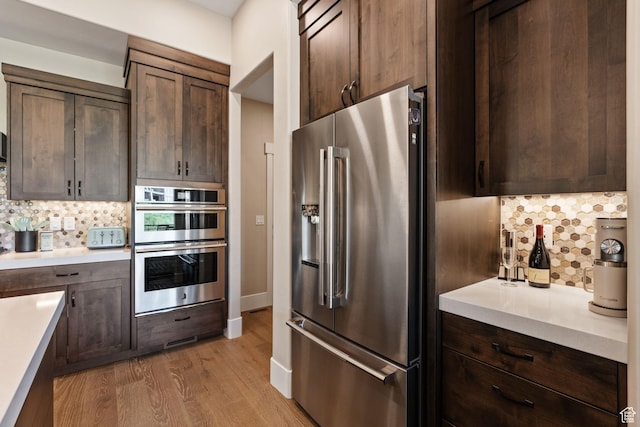 11422 N Vantage Ln Unit 69, Hideout, UT 84036 - kitchen featuring appliances with stainless steel finishes, tasteful backsplash, light wood-type flooring, light countertops, and dark brown cabinetry