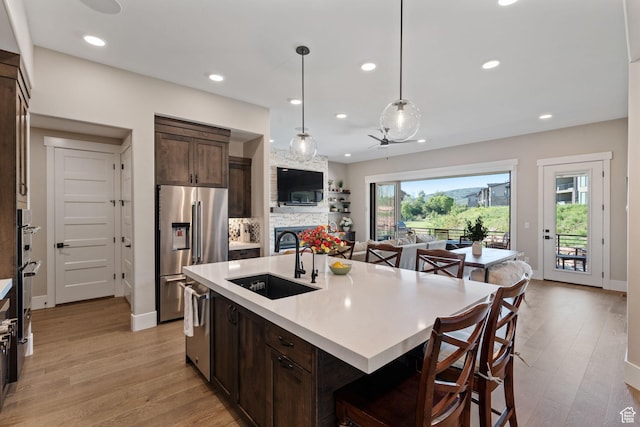 11422 N Vantage Ln Unit 69, Hideout, UT 84036 - kitchen featuring stainless steel appliances, dark brown cabinetry, a breakfast bar, light countertops, and light wood-type flooring