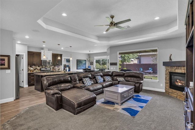 2644 E 3800 S, St George, UT 84790 - living room with a tray ceiling, a ceiling fan, a fireplace, recessed lighting, and light wood-style flooring