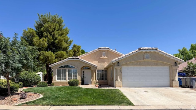 319 E 710 S, Ivins, UT 84738 - mediterranean / spanish house featuring an attached garage, a front lawn, stucco siding, and driveway