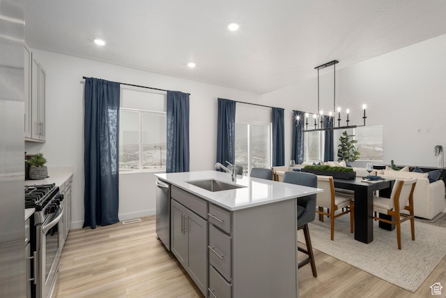 1813 E Bison Dr N Unit B213, Eagle Mountain, UT 84005 - kitchen with appliances with stainless steel finishes, gray cabinets, a breakfast bar, a chandelier, and light wood-style floors