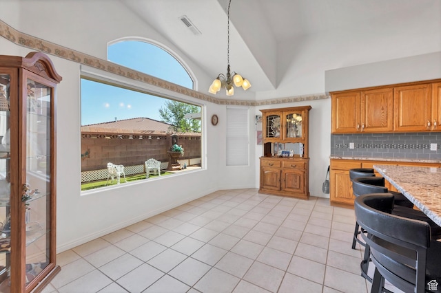3430 Red Butte Dr, Santa Clara, UT 84765 - kitchen featuring lofted ceiling, backsplash, light tile patterned floors, brown cabinetry, and pendant lighting